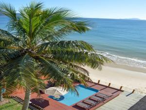 a palm tree next to a beach with a swimming pool at Flat Pietra in Florianópolis