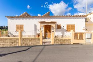 une maison blanche avec un portail et une clôture dans l'établissement Villa Can Benet de sa Cubana by Slow Villas, à Calvià