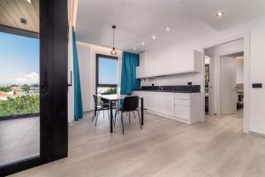 a kitchen with white cabinets and a table with chairs at Residence Cala Vela Tower in Riccione +8 photos