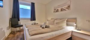 een slaapkamer met 2 bedden, een stoel en een raam bij StrandGut inkl Saisonstrandkorb und Wäsche Set in Heiligenhafen