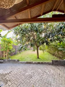 a patio with a tree in the middle of a yard at Desa Huis Yogyakarta in Gandok +21 photos