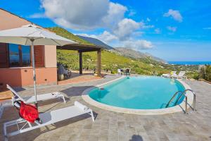 une piscine avec deux chaises et un parasol dans l'établissement Villa Tarì, à Scopello