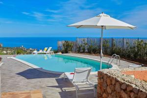 une piscine avec un parasol et deux chaises et une table et un parasol dans l'établissement Villa Tarì, à Scopello