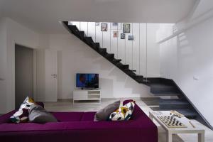 a living room with a purple couch and a staircase at La Suite Di Tyche in Castellammare del Golfo