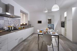 a kitchen with white cabinets and a table and chairs at La Suite Di Tyche in Castellammare del Golfo