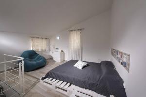 a white bedroom with a bed and a blue chair at La Suite Di Tyche in Castellammare del Golfo