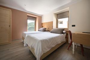a bedroom with two beds and a desk and two windows at Ca del Tusa in Livigno
