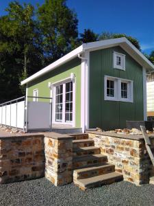 ein grün-weißes Gebäude mit einer Treppe davor in der Unterkunft Ferienhaus in Bad Marienberg Westerwald mit Terrasse und Grill in Bad Marienberg