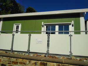 ein grün-weißes Gebäude mit weißen Türen in der Unterkunft Ferienhaus in Bad Marienberg Westerwald mit Terrasse und Grill in Bad Marienberg