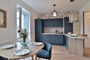 une cuisine avec des armoires bleues et une table et des chaises dans l'établissement La plage du Verger, à Cancale 6 autres photos