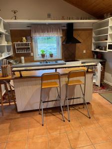 a kitchen with two bar stools at a counter at Nästeviken Björkhaget in Nästeviken