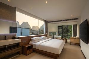 een slaapkamer met een groot bed en een groot raam bij Karst Scenic Hotel in Gaotian