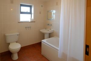 a bathroom with a toilet and a tub and a sink at Station House in Foxford