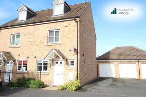 ein Backsteinhaus mit zwei weißen Garagentoren in der Unterkunft 3 Bedroom Contractor House By Your Lettings Short Lets & Serviced Accommodation Peterborough With Free WiFi and Parking in Peterborough