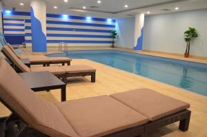 a swimming pool with lounge chairs and a large pool at One to One in Al Khobar