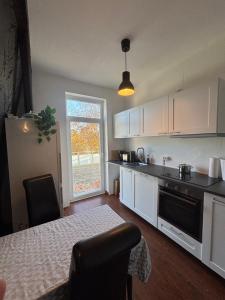 a kitchen with white cabinets and a table and a window at Gästehaus in Kronshagen