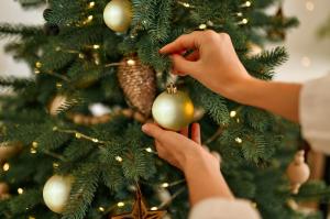 a person putting a christmas ornament on a christmas tree at Villa Vintage, Scandinavian Design and Comfort Near the City and Ski Slopes in Rovaniemi +35 photos