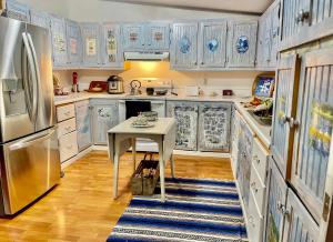 una cucina con mobili blu e bianchi e un tavolo di Mattawamkeag River Cottage a Island Falls