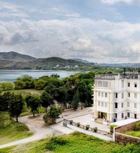 Vista aérea de un edificio blanco y un lago en The Colonial - A Lake View Hotel in Udaipur, en Udaipur