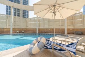 a swimming pool with a chair and an umbrella at Urban Chic - Mangrove Place in Abu Dhabi +8 photos