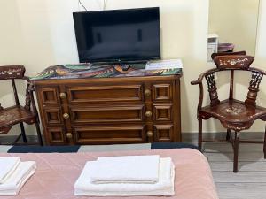 einen TV auf einer Kommode mit 2 Stühlen in der Unterkunft Lili & Aurora Home in Rom