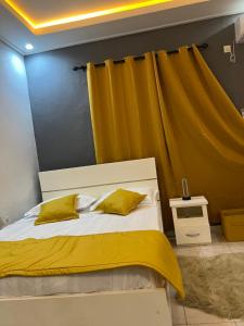 een slaapkamer met een bed met een geel gordijn bij Tataicha Stydio 1 in Ndjamena