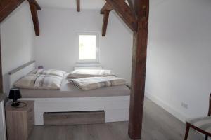 a bed in a white room with a window at Alt-Berliner Schwanenhof Ferienwohnung DG rechts in Lychen