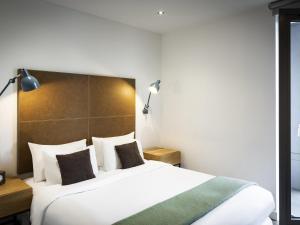 a bedroom with a large white bed with two pillows at Aparthotel Adagio London Brentford in Brentford