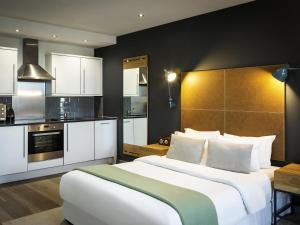 a bedroom with a large bed and a kitchen at Aparthotel Adagio London Brentford in Brentford