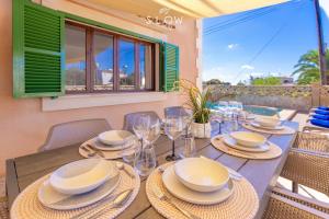 a wooden table with plates and glasses on it at Villa Sa Llimonera by Slow Villas in Llombarts
