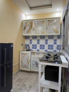 een keuken met witte kasten en een zwarte koelkast bij Tataicha Stydio 1 in Ndjamena
