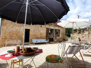 una mesa con sombrilla y sillas y una mesa con un bol de fruta en Gîte charmant à Groléjac avec parking, WiFi et jardin clos - FR-1-616-428, en Groléjac