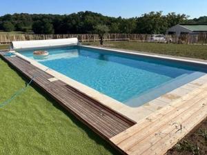 a large swimming pool with a wooden deck in a yard at Maison charmante avec piscine partagée et wifi à Brantôme, pour 8 personnes - FR-1-616-441 in Puyjoubert