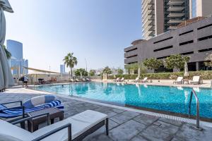 a large swimming pool with chairs and a building at Urban Chic - Shams Meera in Abu Dhabi +10 photos