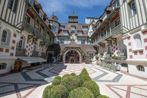 an empty courtyard of a large building with bushes at L'intemporel YourHostHelper in Deauville