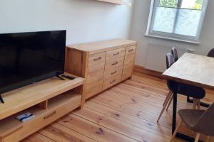 - un salon avec une télévision à écran plat sur un centre de divertissement en bois dans l'établissement Alt-Berliner Schwanenhof Ferienwohnung EG rechts, à Lychen