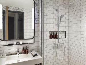 Un baño blanco con lavabo y ducha. en Mövenpick Hotel The Hague, en La Haya