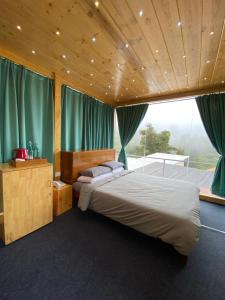 ein Schlafzimmer mit einem Bett und einem großen Fenster in der Unterkunft COTTAGES BY THE CREEK. in Kodaikanal