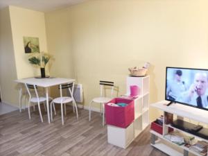 ein Wohnzimmer mit einem TV und einem Tisch mit Stühlen in der Unterkunft Près Gare T2 42m2 avec jardinet-terrasse 10m2 in Angoulême