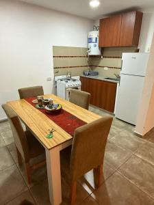 a kitchen with a wooden table with chairs and a kitchen with a refrigerator at La posada de Majo 1 in Pergamino +7 photos