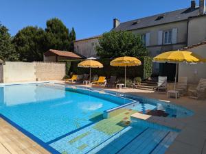 einen Pool mit 2 Sonnenschirmen und Stühlen in der Unterkunft Gîte familial avec piscine chauffée, jardin privé et équipements bébé en pleine propriété viticole. - FR-1-653-18 in Saint-Cybardeaux