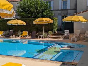 a swimming pool with two umbrellas and chairs at Maison de charme avec piscine chauffée et jardin privé, idéale pour familles - FR-1-653-85 in Saint-Cybardeaux