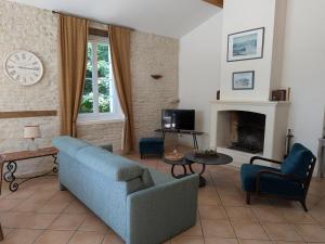 ein Wohnzimmer mit einer blauen Couch und einem Kamin in der Unterkunft Gîte familial avec piscine chauffée, jardin clos, équipement bébé, au cœur d'une propriété viticole. - FR-1-653-70 in Saint-Cybardeaux
