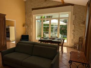 ein Wohnzimmer mit einem Sofa und einem Tisch mit einem Sonnenschirm in der Unterkunft Gîte familial avec piscine chauffée, jardin clos, équipement bébé, au cœur d'une propriété viticole. - FR-1-653-70 in Saint-Cybardeaux