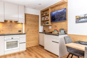 a kitchen with white cabinets and a dining table at DAS EDELWEISS - Apartment Kuprian in Ried im Oberinntal