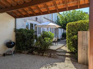 an outdoor patio with an umbrella and a grill at Maison de charme avec piscine chauffée et jardin privé, idéale pour familles - FR-1-653-85 in Saint-Cybardeaux