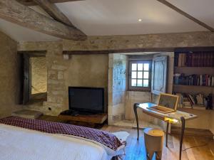 a bedroom with a bed and a laptop on a desk at Prieuré restauré avec jardin, charme ancien et commodités modernes, près de l’église à Beaulieu - FR-1-653-145 in Beaulieu-sur-Sonnette