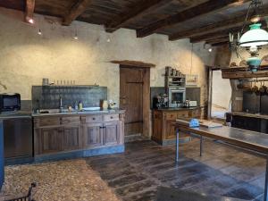 a large kitchen with wooden cabinets and a table at Prieuré restauré avec jardin, charme ancien et commodités modernes, près de l’église à Beaulieu - FR-1-653-145 in Beaulieu-sur-Sonnette