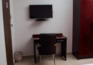 a desk with a chair and a television on a wall at Fanky Hotel in Palatswe
