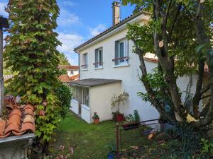 a white house with a tree in the yard at Charmant Gîte avec Terrasse et Jardin, Proche Centre - FR-1-653-196 in Barbezieux